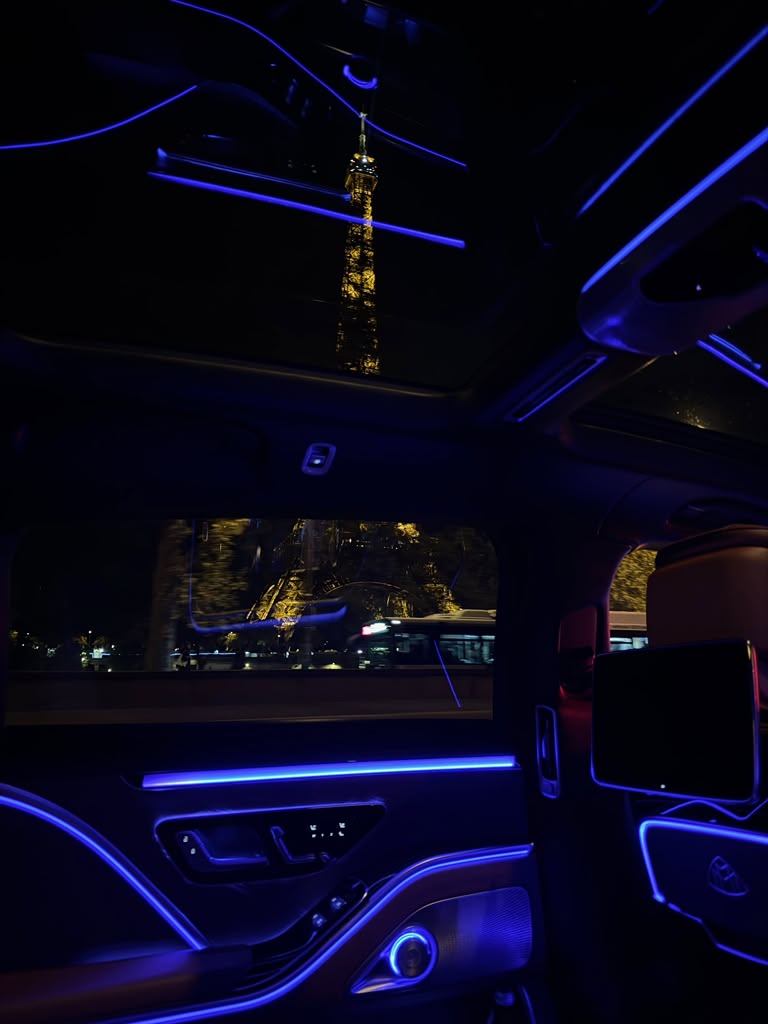Full portrait view of the illuminated Eiffel Tower from inside a luxury car at night